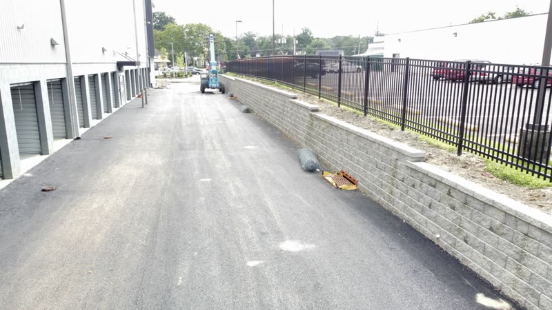 Black aluminum fence on top of a retaining wall beside a commercial lot