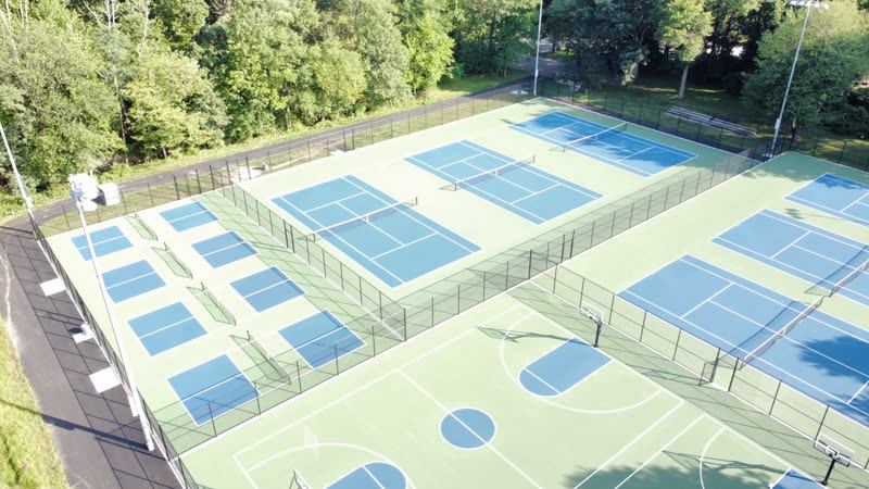 Aerial view of tennis and basketball courts with black fencing