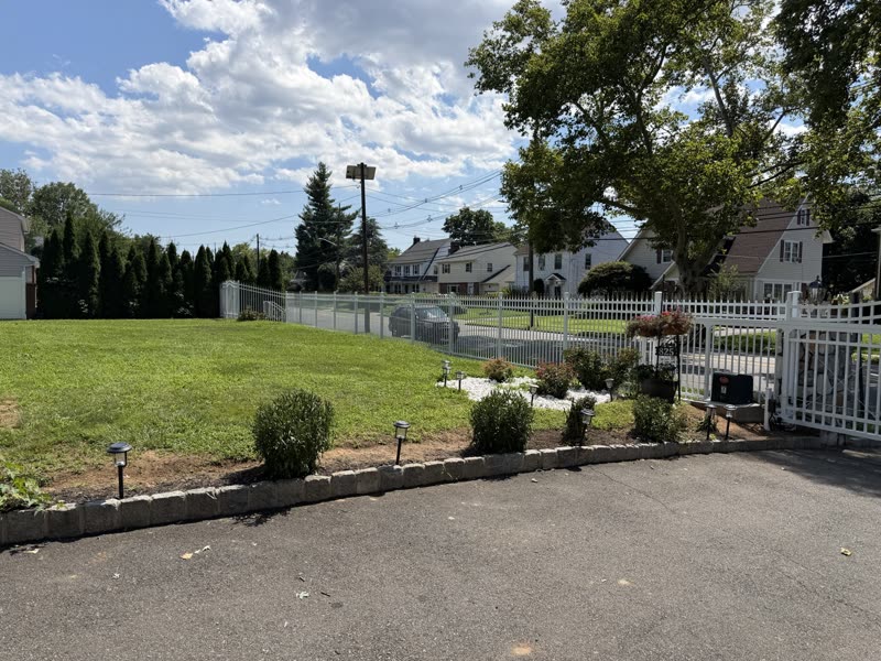 White fence with planting beds and a driveway