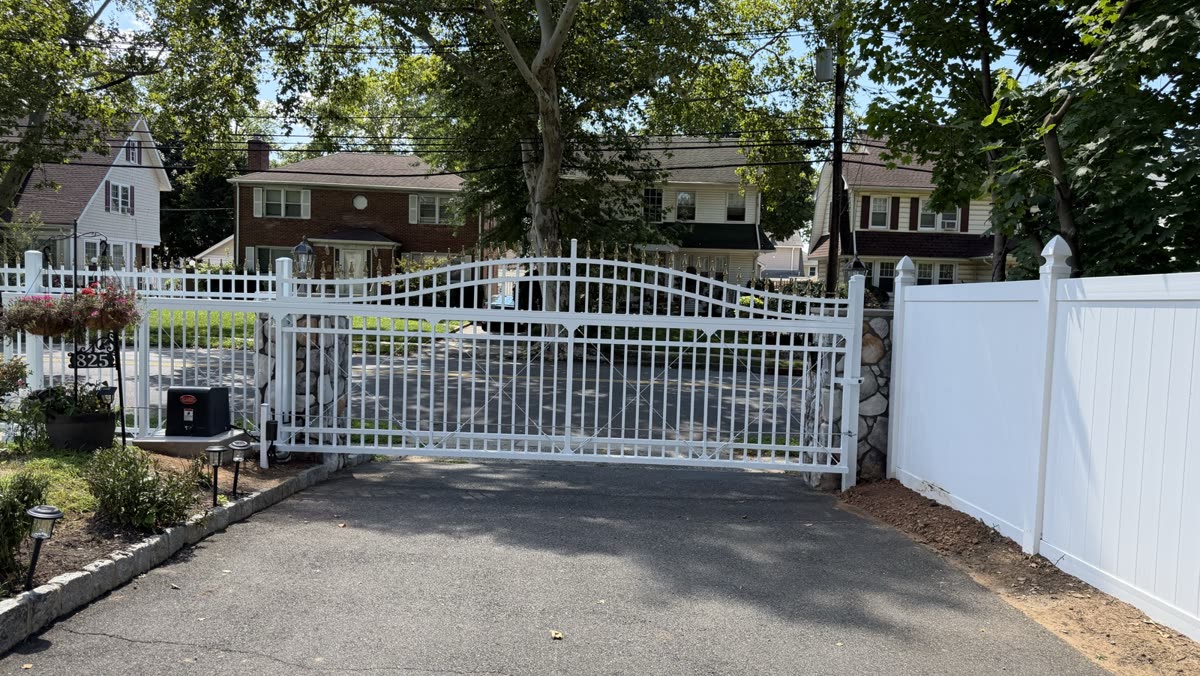 White arched double driveway gate with a stone pillar