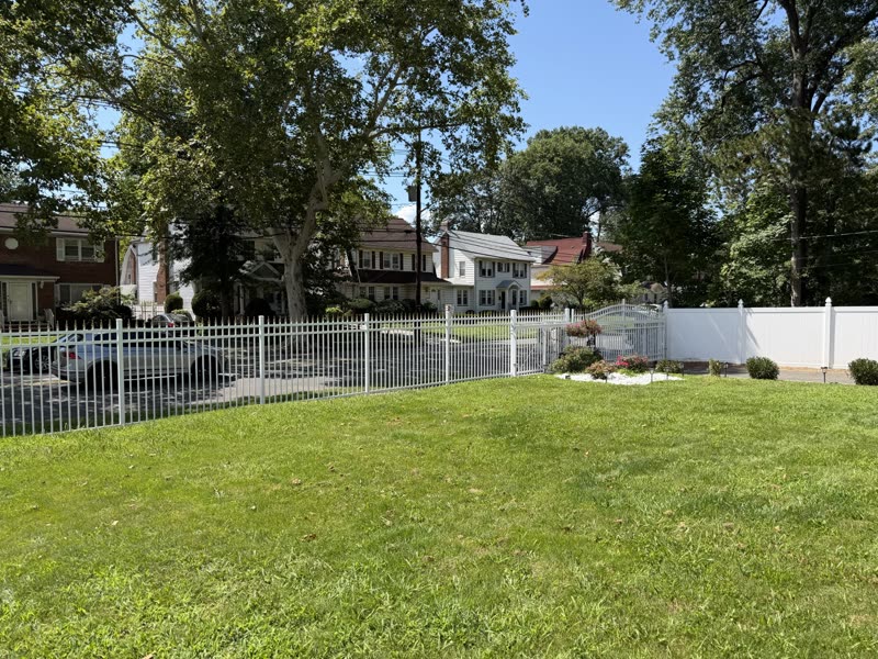 White aluminum fence along a front lawn