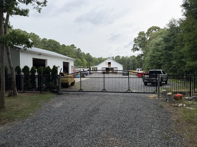 Black double driveway gate on a gravel drive