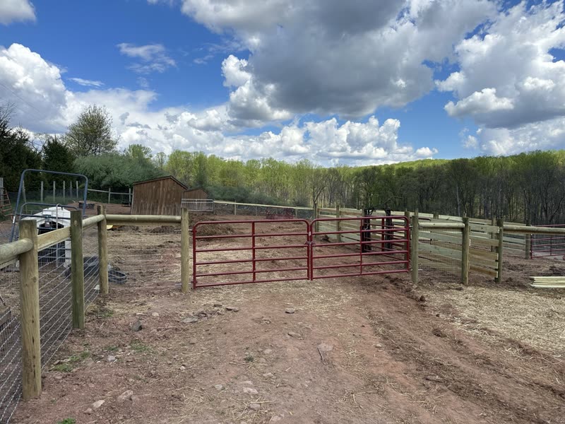 Wood rail ranch fence with a red gate