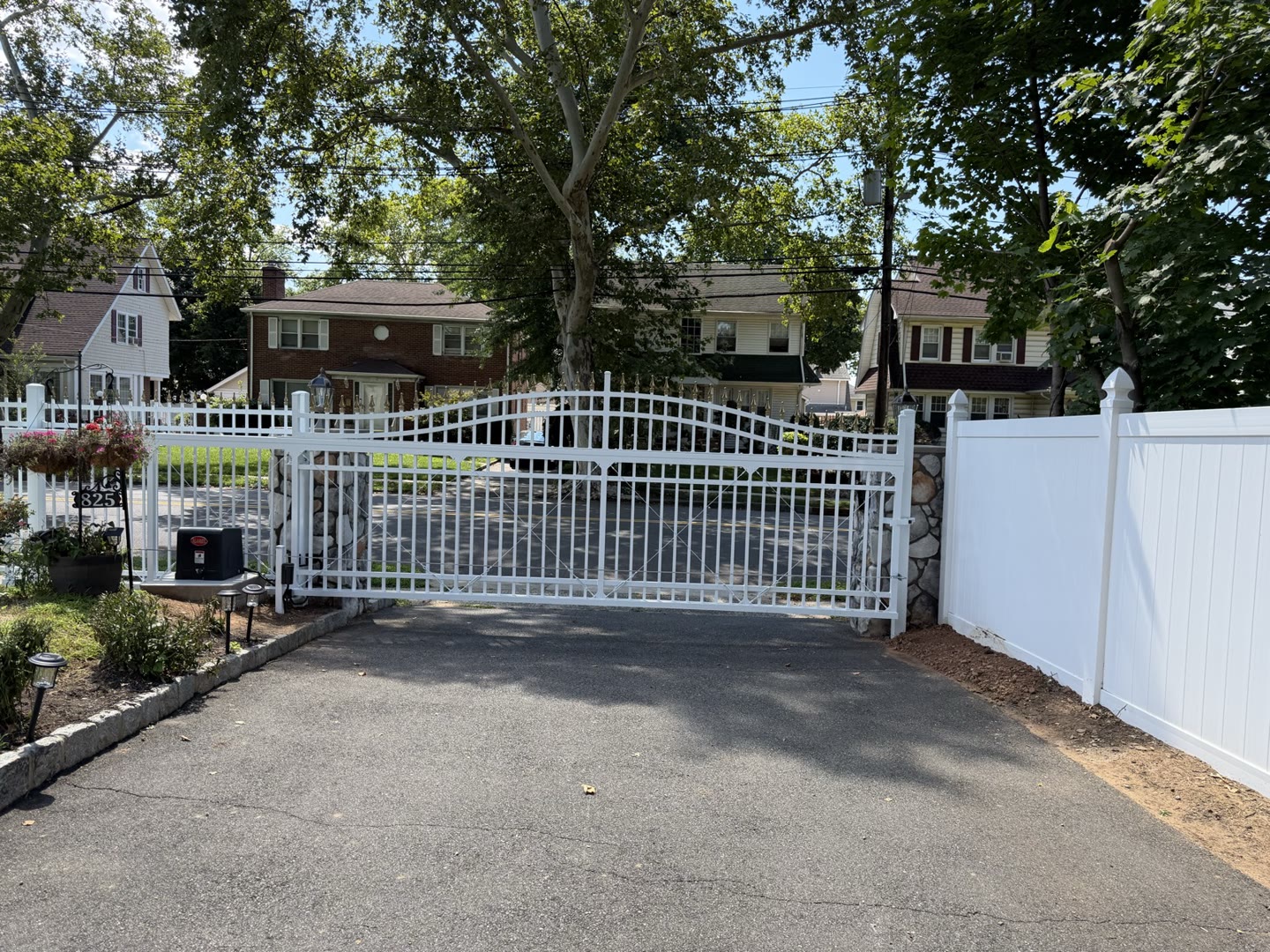 White arched double driveway gate with a stone pillar