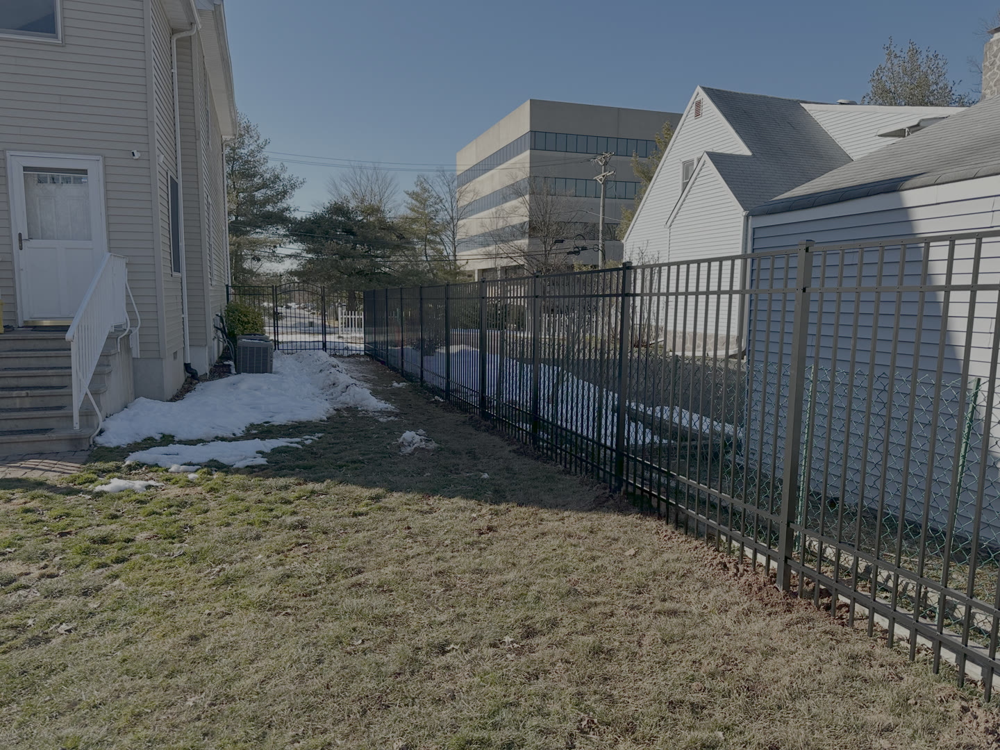 Black aluminum fence standing straight in a snowy New Jersey yard