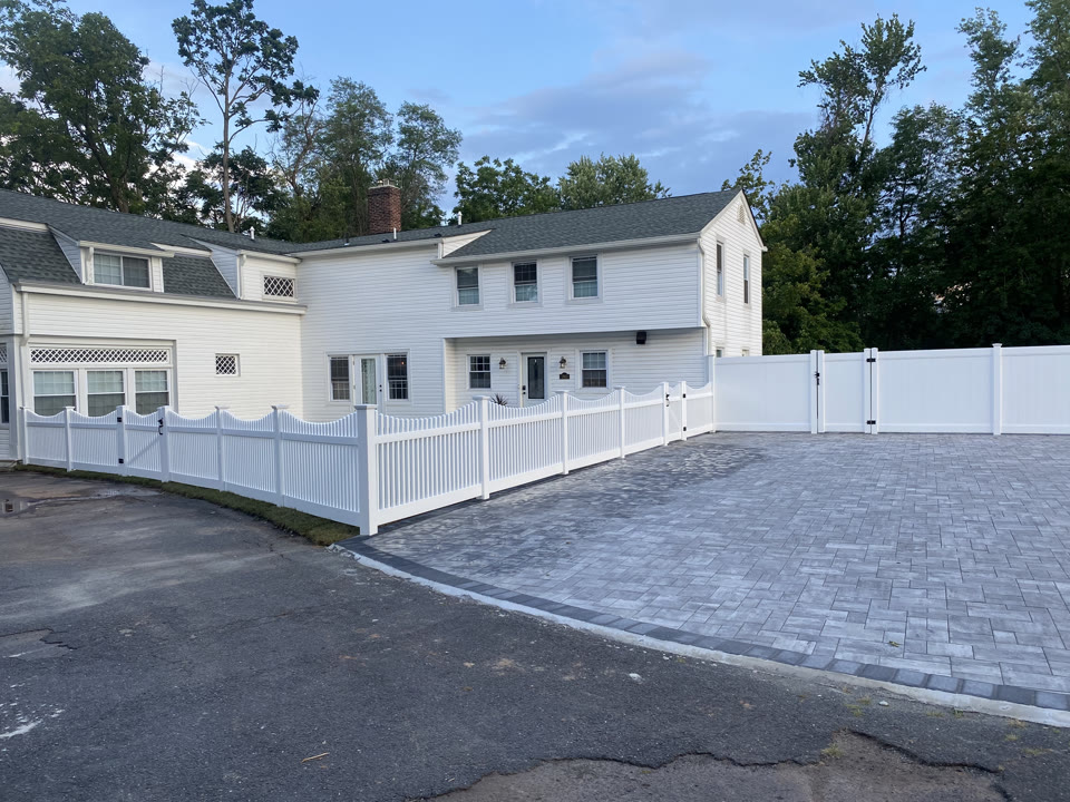 White vinyl fence beside a paver driveway