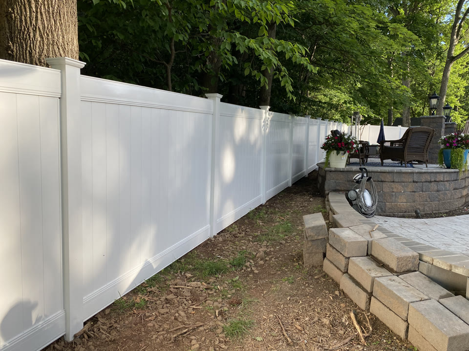 White vinyl privacy fence beside a stone patio